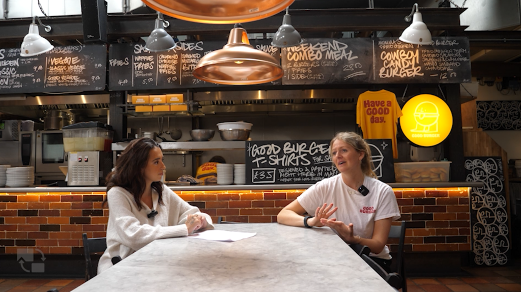 Jess, the manager of Good Burger in an interview at a table in front of Good Burger